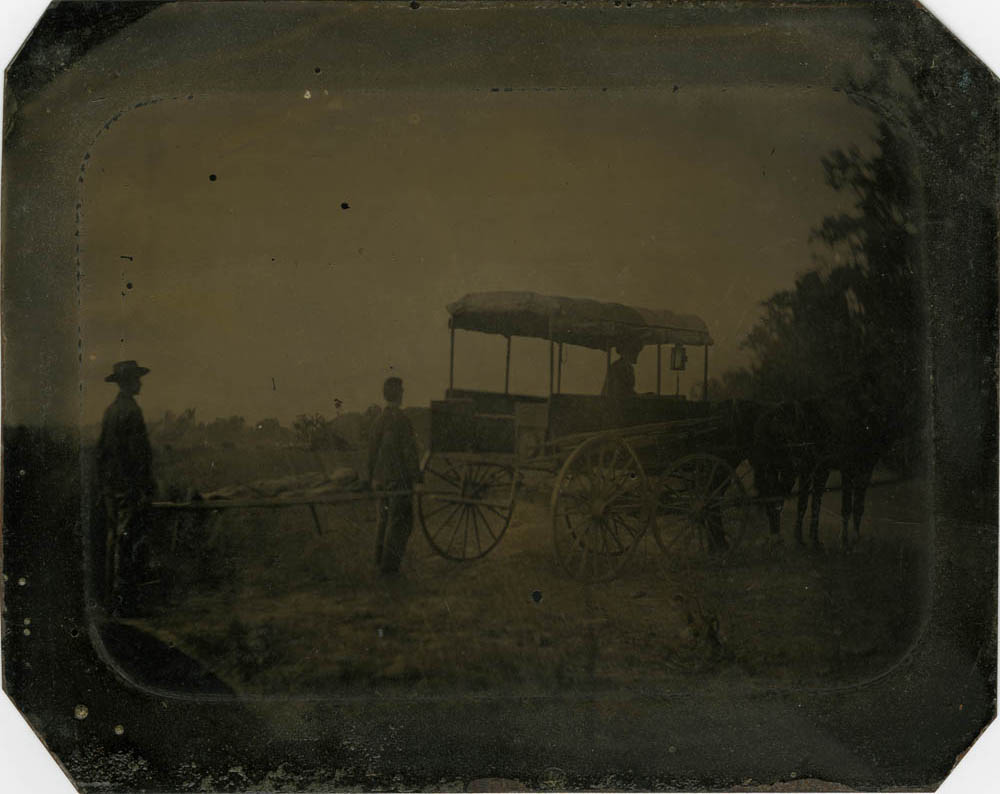 Two men standing next to ambulance wagon.