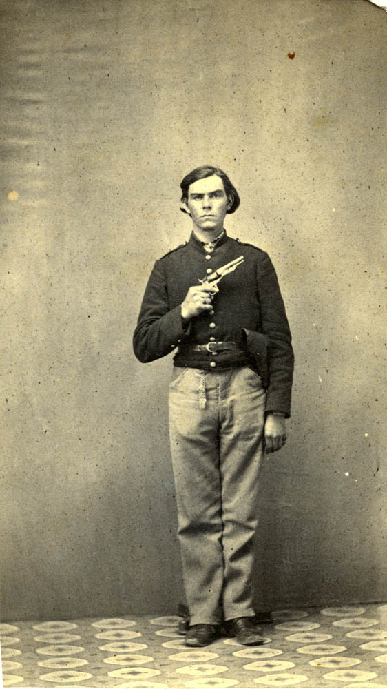 George Hudson standing in uniform with revolver.